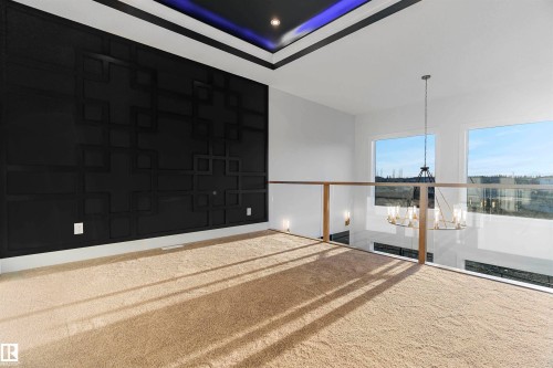 Open concept space featuring a dark accent wall with geometric paneling, tray ceiling with ambient lighting, and large windows providing natural light - 368 Creekside Green, Leduc, AB - Outdoor With Exterior