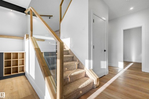 Entryway featuring light hardwood flooring, a staircase with carpeted treads and a wooden and glass railing, and built-in shelving - 368 Creekside Green, Leduc, AB - Indoor Photo Showing Other Room