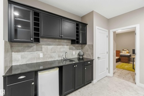 The property features a well-appointed wet bar with dark cabinetry, a built-in wine rack, a sink with a faucet, and a compact refrigerator - 5014 Dewolf Road, Edmonton, AB 