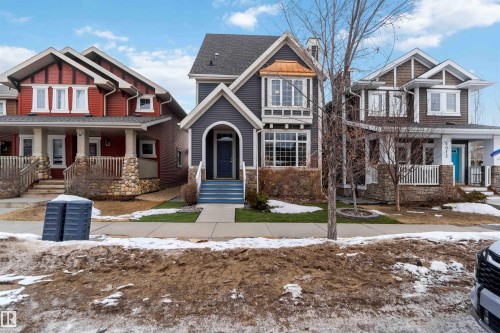 The property features a charming exterior with a dark blue siding, a welcoming front door, and a decorative copper bay window - 5014 Dewolf Road, Edmonton, AB 