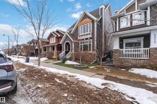 This property features a stone and siding exterior, a front porch with white railings, and a meticulously maintained lawn area - 5014 Dewolf Road, Edmonton, AB 