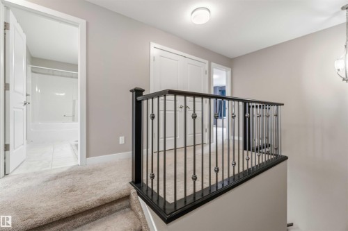 This property features a landing with carpeted flooring and a wrought iron railing - 5014 Dewolf Road, Edmonton, AB 