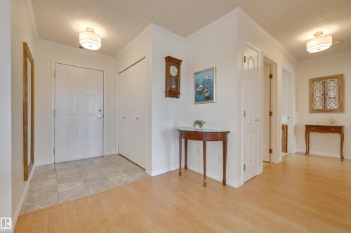 This inviting entryway features light-colored flooring, including both tile and wood, complemented by neutral wall tones - 304 17151 94A Avenue, Edmonton, AB - Indoor Photo Showing Other Room