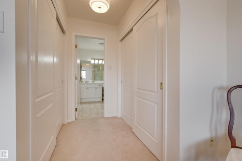 Hallway featuring light-colored carpet flooring and white closet doors - 304 17151 94A Avenue, Edmonton, AB - Indoor Photo Showing Other Room
