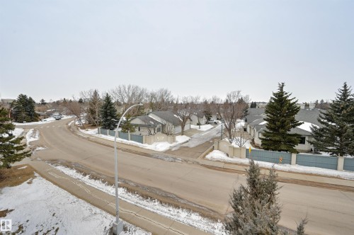 View of the neighborhood featuring paved roads, sidewalks, and surrounding properties with green trees - 304 17151 94A Avenue, Edmonton, AB - Outdoor With View