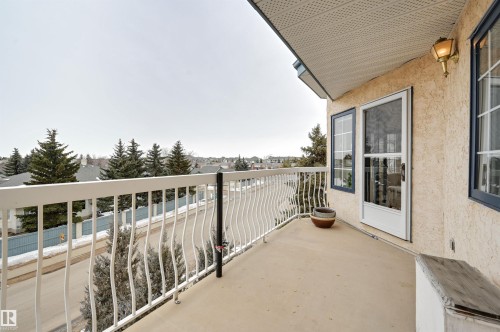 The property features an exterior balcony with a white railing, providing views of the surrounding neighborhood with visible trees and residential structures - 304 17151 94A Avenue, Edmonton, AB - Outdoor With Balcony With Exterior