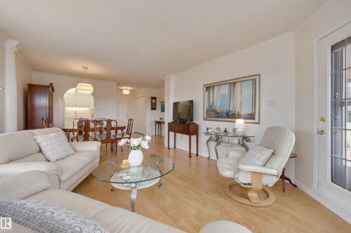The living area features light-toned flooring, white walls, and crown molding - 304 17151 94A Avenue, Edmonton, AB - Indoor Photo Showing Living Room