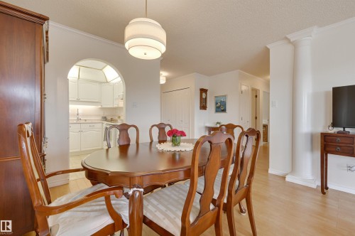 This dining area features hardwood flooring, an arched doorway, and a contemporary ceiling light fixture - 304 17151 94A Avenue, Edmonton, AB - Indoor Photo Showing Dining Room