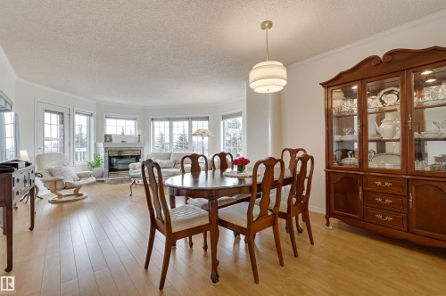 The property features light-toned wood flooring throughout, with a dining area illuminated by a contemporary ceiling fixture - 304 17151 94A Avenue, Edmonton, AB - Indoor Photo Showing Dining Room