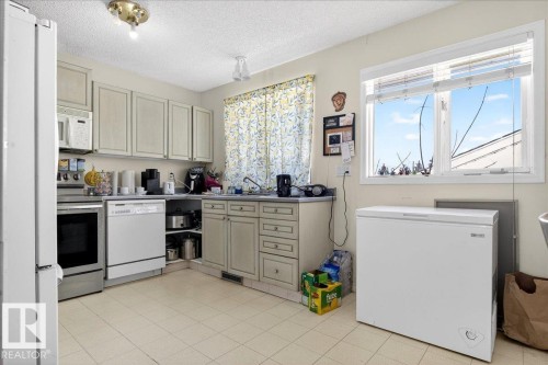 Kitchen with light-colored cabinetry, tile flooring, and a window providing natural light - 13304 130 Avenue, Edmonton, AB - Indoor