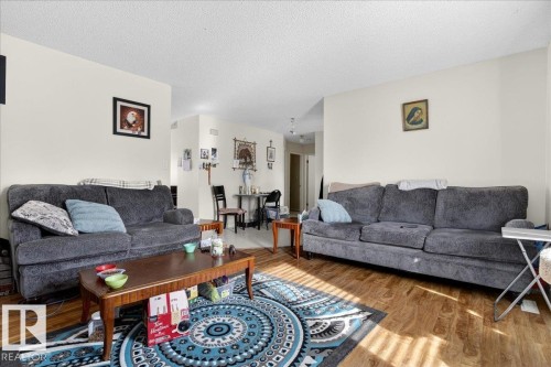 This living area features light-colored walls and wood-style flooring, offering a versatile foundation for various design preferences - 13304 130 Avenue, Edmonton, AB - Indoor Photo Showing Living Room