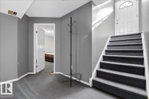 Entryway featuring carpeted flooring and a staircase leading to a white door with an arched window - 13304 130 Avenue, Edmonton, AB - Indoor Photo Showing Other Room