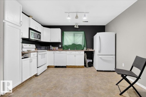 The kitchen features white cabinetry, white appliances, and track lighting - 13304 130 Avenue, Edmonton, AB - Indoor Photo Showing Kitchen