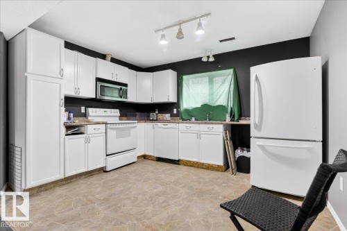 The kitchen features white cabinetry, a white refrigerator, and a white oven - 13304 130 Avenue, Edmonton, AB - Indoor Photo Showing Kitchen