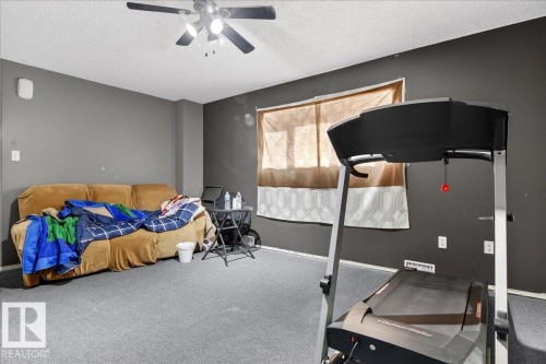 The room features a ceiling fan, dark grey walls, and light grey carpeting - 13304 130 Avenue, Edmonton, AB - Indoor Photo Showing Bedroom