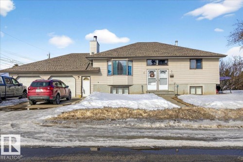 The property features a two-car garage with a paved driveway, and a light-colored siding exterior - 13304 130 Avenue, Edmonton, AB - Outdoor