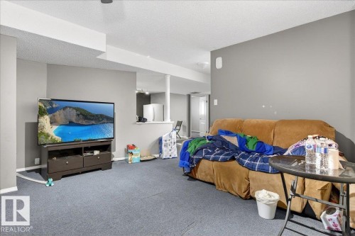 Spacious room featuring gray walls, blue carpet, and white trim - 13304 130 Avenue, Edmonton, AB - Indoor
