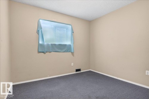 The room features a window with a blue covering, light-colored walls, and a gray carpet - 13304 130 Avenue, Edmonton, AB - Indoor Photo Showing Other Room