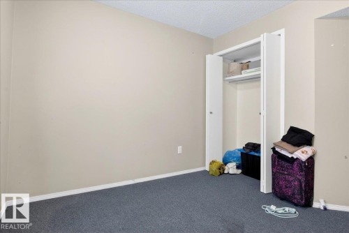 The room features a neutral wall color, dark gray carpeting, and a closet with bifold doors and an interior shelf - 13304 130 Avenue, Edmonton, AB - Indoor Photo Showing Other Room