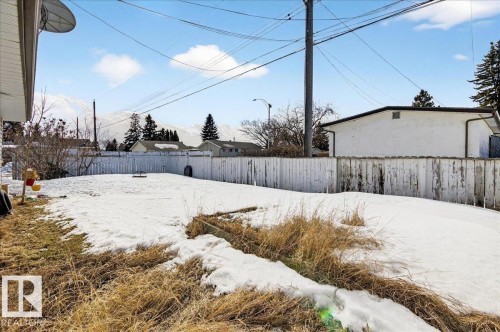 The property includes a spacious yard with a white picket fence, offering views of distant mountains - 13304 130 Avenue, Edmonton, AB - Outdoor