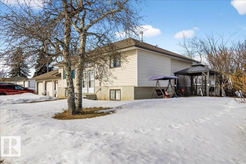 The property features a light-colored exterior with a brown roof and a detached garage - 13304 130 Avenue, Edmonton, AB - Outdoor