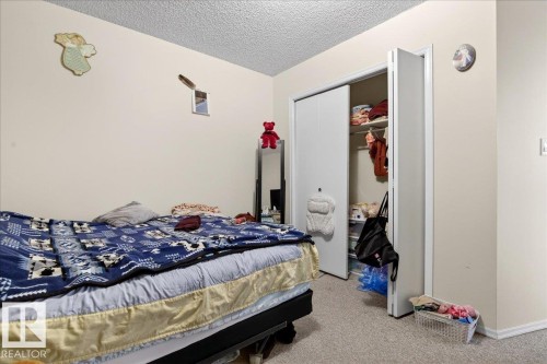 This room features neutral-toned walls, carpeted flooring, and a closet with bifold doors - 13304 130 Avenue, Edmonton, AB - Indoor Photo Showing Bedroom