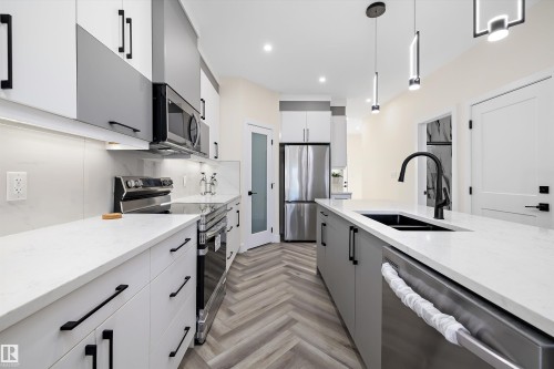 The kitchen features a contemporary design with two-tone cabinetry, stainless steel appliances, and sleek countertops - 8321 81Ave, Edmonton, AB - Indoor Photo Showing Kitchen With Double Sink With Upgraded Kitchen