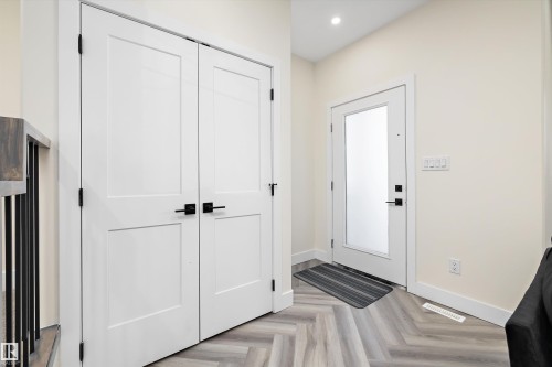 Entryway featuring light-toned walls, a white front door with a frosted glass panel, and light-toned flooring in a herringbone pattern - 8321 81Ave, Edmonton, AB - Indoor Photo Showing Other Room