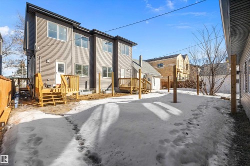 The property features a multi-story exterior with horizontal siding, multiple windows, and a wooden deck with stairs - 8321 81Ave, Edmonton, AB - Outdoor