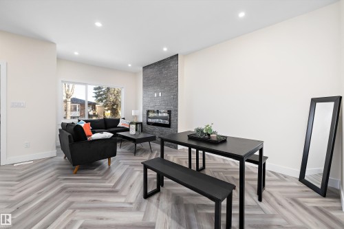 Living area featuring herringbone-patterned flooring, a stone-accented fireplace, and recessed lighting - 8321 81Ave, Edmonton, AB - Indoor Photo Showing Living Room With Fireplace