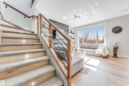 The property features a staircase with carpeted treads and hardwood risers, complemented by a contemporary railing with wooden handrails and black spindles - 1531 151 Avenue, Edmonton, AB - Indoor
