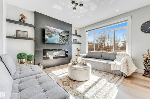 The living area features light-toned flooring, a fireplace with a dark-toned surround, and a large window providing views of the outdoors - 1531 151 Avenue, Edmonton, AB - Indoor Photo Showing Living Room With Fireplace