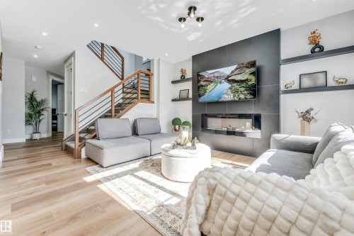 Living area featuring light wood flooring, a fireplace with a dark tiled surround, and recessed lighting - 1531 151 Avenue, Edmonton, AB - Indoor Photo Showing Living Room With Fireplace