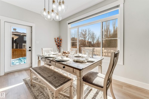 This dining area features hardwood floors and a modern light fixture with multiple clear glass globes - 1531 151 Avenue, Edmonton, AB - Indoor Photo Showing Dining Room