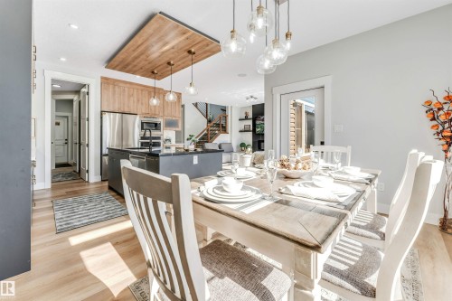 Open concept dining area and kitchen featuring hardwood flooring, a dining table with chairs, and overhead lighting - 1531 151 Avenue, Edmonton, AB - Indoor Photo Showing Dining Room