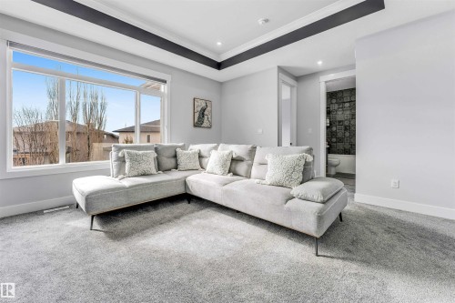 This living space features a large window with views of the surrounding neighborhood, light grey carpeting, and a tray ceiling with dark trim - 1531 151 Avenue, Edmonton, AB - Indoor Photo Showing Living Room