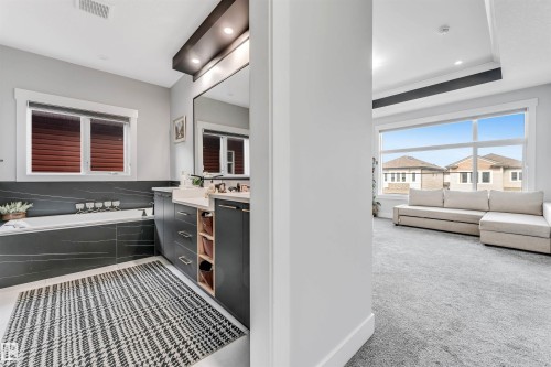 Spacious bathroom featuring a built-in bathtub with dark tiled surround and a vanity with dual sinks - 1531 151 Avenue, Edmonton, AB - Indoor