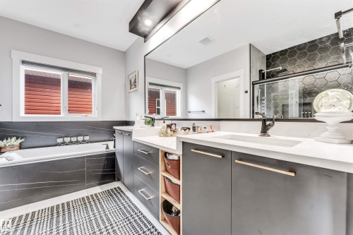 Spacious bathroom featuring a large soaking tub, a double vanity with a quartz countertop and modern cabinetry, and a walk-in shower with hexagonal tiling - 1531 151 Avenue, Edmonton, AB - Indoor Photo Showing Bathroom