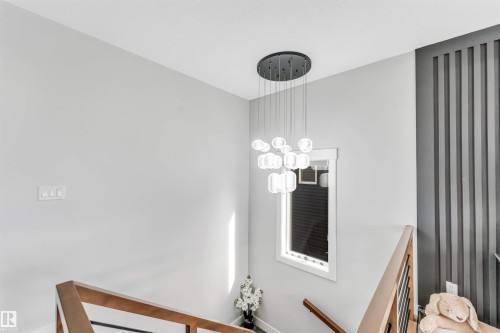 The property features a contemporary chandelier, a window with white trim, and a decorative wall panel - 1531 151 Avenue, Edmonton, AB - Indoor Photo Showing Other Room