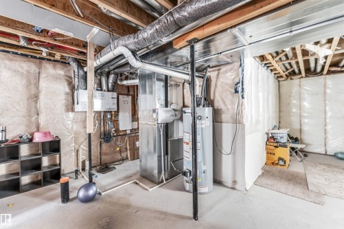 The property features a utility area with exposed ceiling joists, insulation, and a water heater - 1531 151 Avenue, Edmonton, AB - Indoor Photo Showing Basement