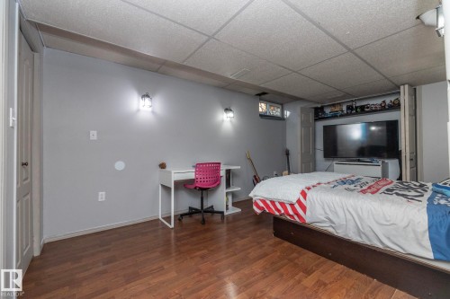 A bedroom space featuring light gray walls, warm-toned wood flooring, and a drop ceiling - 6 Glaewyn Estates, St. Albert, AB - Indoor Photo Showing Bedroom