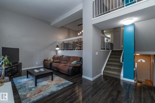 Living area featuring dark wood floors, a high ceiling, and a staircase with white railings - 6 Glaewyn Estates, St. Albert, AB - Indoor
