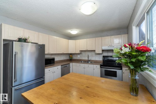 The kitchen features light-colored cabinetry, a stainless steel refrigerator, and a stainless steel oven with a range hood - 6 Glaewyn Estates, St. Albert, AB - Indoor Photo Showing Kitchen With Double Sink
