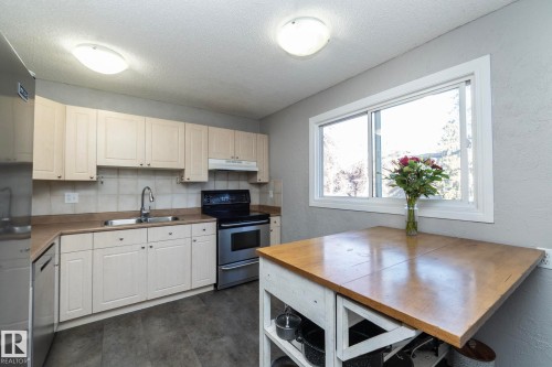 Kitchen featuring light-toned cabinetry, stainless steel appliances, a window providing natural light, and a wooden-topped island - 6 Glaewyn Estates, St. Albert, AB - Indoor Photo Showing Kitchen With Double Sink