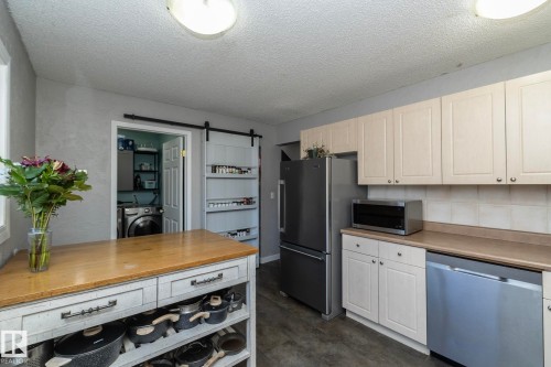 The kitchen features light-colored cabinetry, a stainless steel refrigerator, and a dishwasher - 6 Glaewyn Estates, St. Albert, AB - Indoor Photo Showing Kitchen