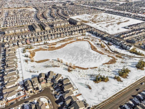 An aerial view showcasing a residential area with a prominent, frozen pond surrounded by snow-covered ground and scattered trees - 1624 33A Street, Edmonton, AB -  With View