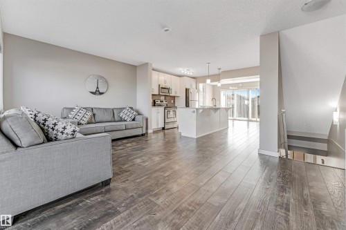 Open concept living area featuring wood style flooring, neutral wall paint, and a bright kitchen with a center island - 1624 33A Street, Edmonton, AB - Indoor Photo Showing Living Room