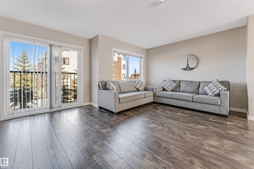 Living area featuring dark wood-style flooring, light neutral walls, and a large window with vertical blinds - 1624 33A Street, Edmonton, AB - Indoor Photo Showing Living Room