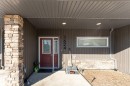 The property features an inviting entrance with a deep red door, vertical siding, and a stone column - 1624 33A Street, Edmonton, AB  - Outdoor 