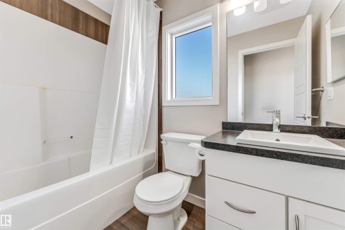 Bathroom featuring a white bathtub and shower with a shower curtain, a toilet, and a vanity with a sink - 1624 33A Street, Edmonton, AB - Indoor Photo Showing Bathroom